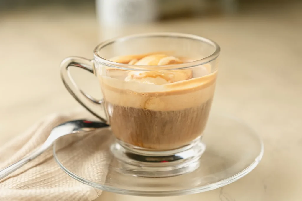 Affogato served in a glass cup on a saucer.