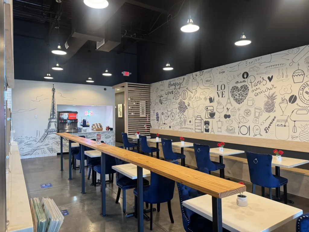 Blue chairs and dining tables beside the mural wall at Taste of Paris.