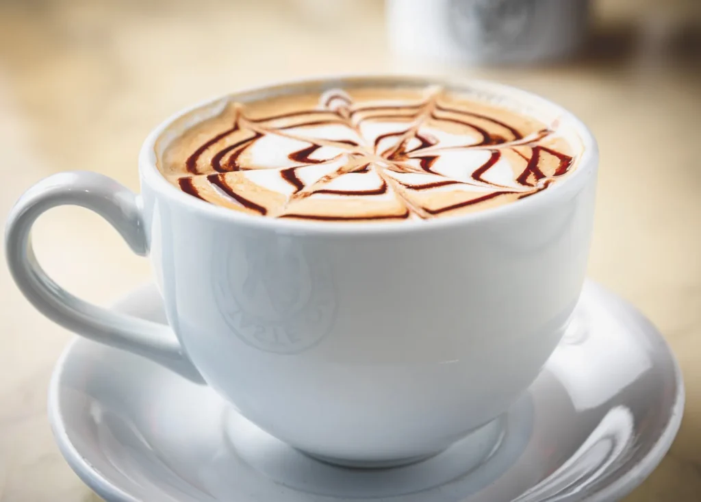 Latte with decorative drizzle in a white cup.
