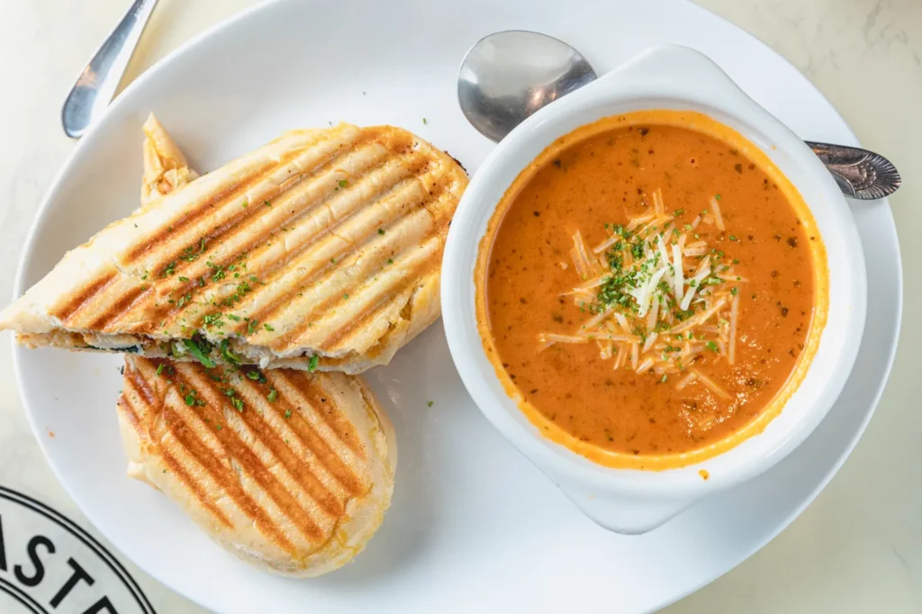Grilled Medi-Terrano panini served beside a bowl of soup.