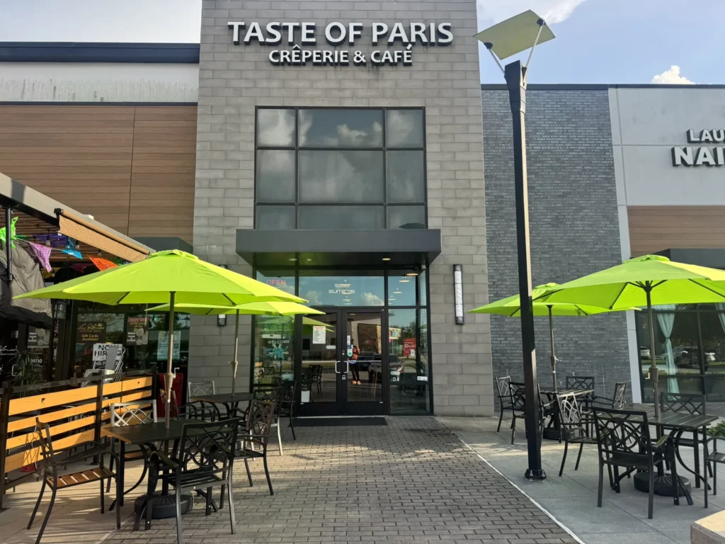 Taste of Paris storefront and outdoor seating with green umbrellas.