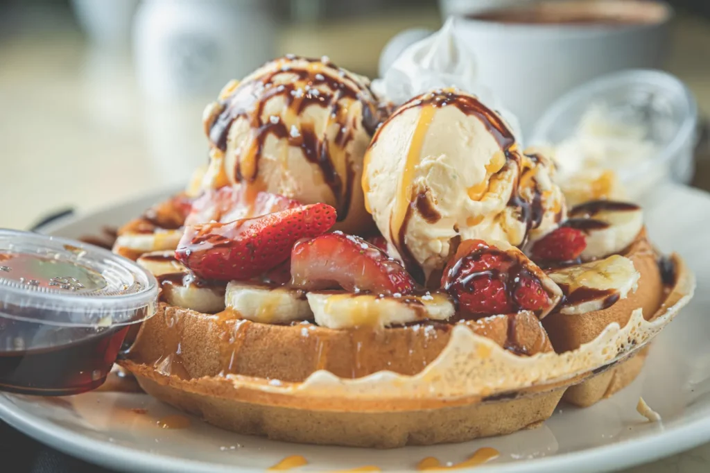 Waffles topped with ice cream, strawberries, bananas and chocolate drizzle.